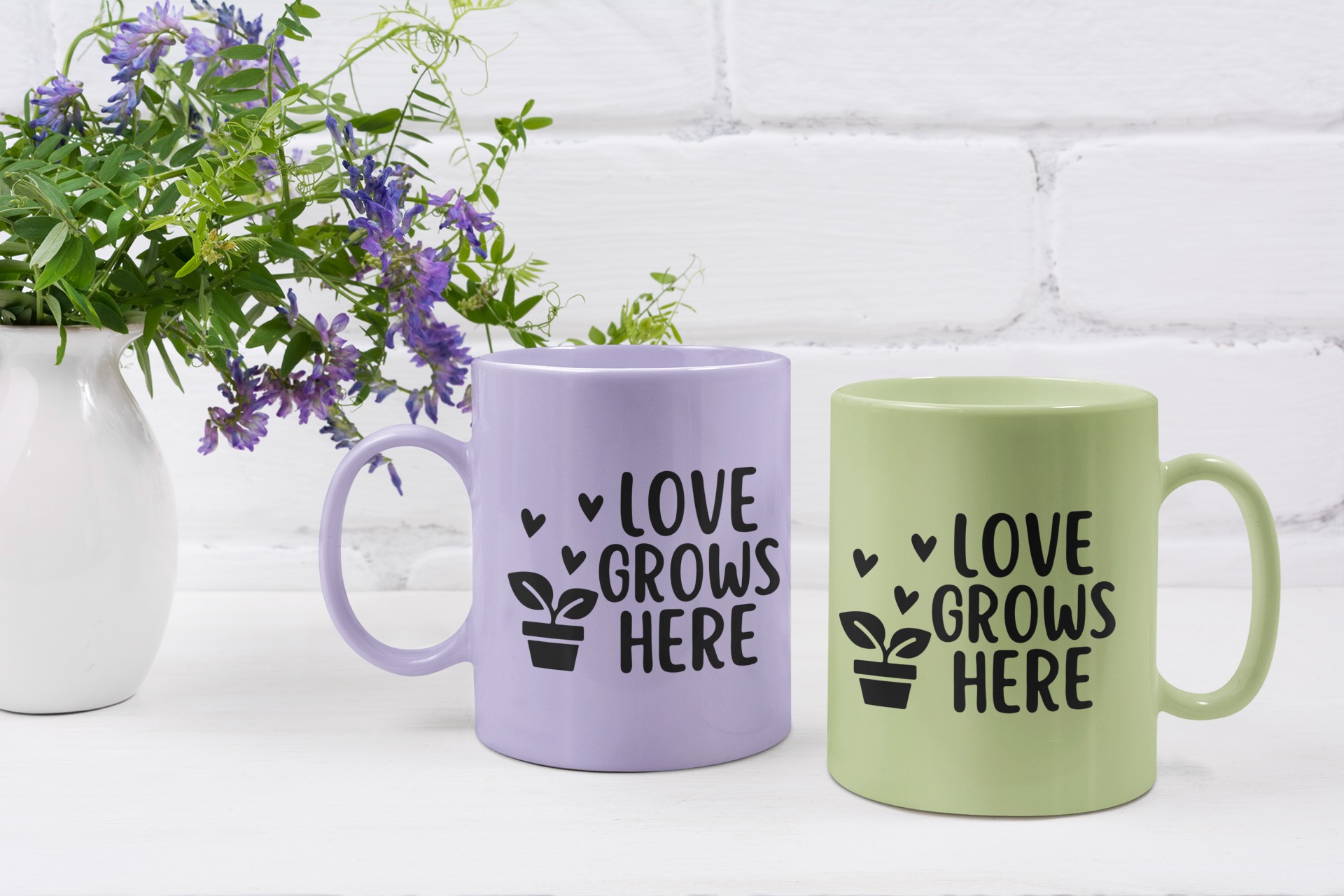 Spring-themed pastel mugs in lavender and green featuring 'Love Grows Here' design with a potted plant and heart accents, perfect for Cricut and Silhouette vinyl crafts.